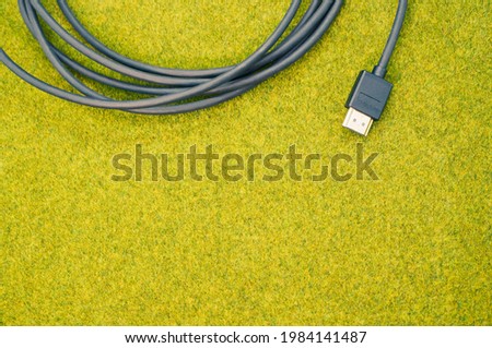 A top view shot of a rolled black cable on a green grass surface