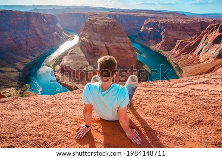 Rear view of a young man sitting with a view of the Horseshoe Bend in Page, Arizona Royalty-Free Stock Photo #1984148711