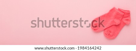 Kid short socks on light pink table background. Pastel color. Closeup. Clothes wide banner. Empty place for text.