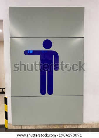 Men restroom sign with white wall as background. Male toilet symbol at the airport. 