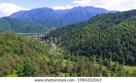 Aerial drone flying above Calinesti valley in Cozia Mountains. Calinesti village can be seen in the background, at the feet of Cozia Massif's rocky crests. Carpathia, Romania. Royalty-Free Stock Photo #1984202063