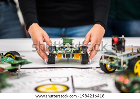 A mechatronic robot with artificial intelligence on wheels thrown by a woman's hands on a table with a canvas.