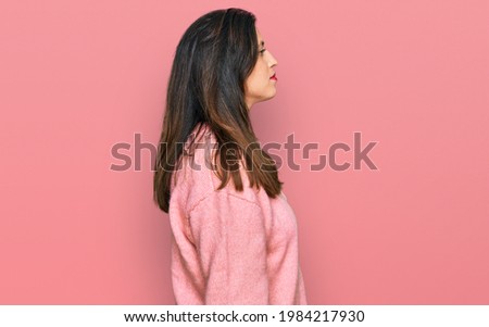Beautiful hispanic woman wearing casual winter sweater looking to side, relax profile pose with natural face with confident smile. 