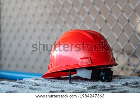 A red safety working helmet for supervisor PIC (person in charge) is placed on the brick block. Construction industrial equipment object photo.