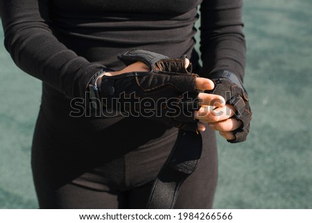 Sportswoman taking off gloves, close-up. Women's hands in sports gloves. Outdoor workout. End of training concept.
