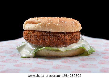 Chicken burger with mayonnaise and lettuce, black background
