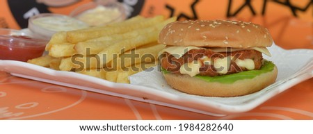 top view of french fries with delicious burger chickenon tray and assorted sauces  
