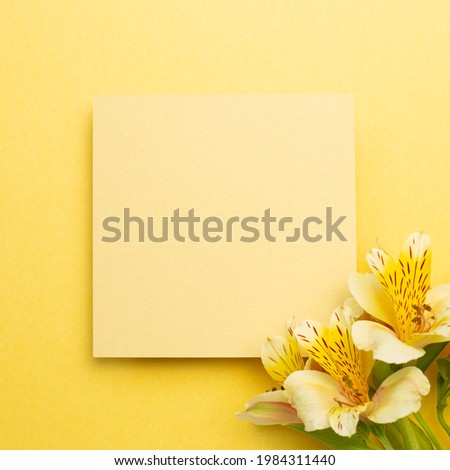 Memo pad with Alstroemeria flowers on yellow background. top view, copy space