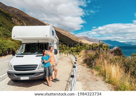 Motorhome RV camper van road trip on New Zealand. Young couple on travel vacation adventure. Two tourists looking at Lake Pukaki and mountains on enjoying view and break next to rental car Royalty-Free Stock Photo #1984323734