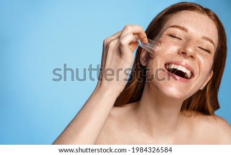 Skin care. Happy woman doing facial cupping massage at home, using vacuum suction cup and laughing, smiling white teeth. Redhead girl facelift massaging with silicone cup, blue background Royalty-Free Stock Photo #1984326584