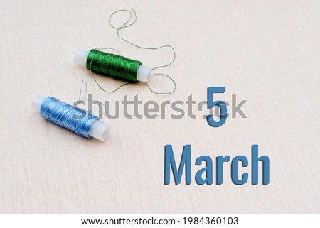 Handicraft calendar 5 march. Skeins of green and blue threads for embroidery on beige background. Handmade concept.