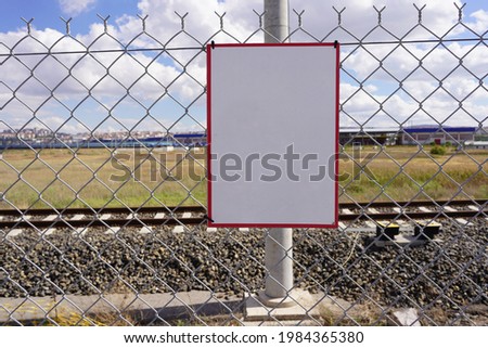 A blank white sign on a metal wire mesh fence