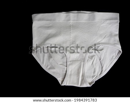 close beige seamless female high-waisted panties lie on a black background top view. women panties with microfiber Royalty-Free Stock Photo #1984391783