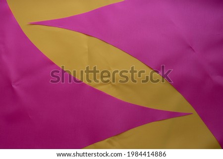 Pink pieces of fabric lie on the yellow fabric.