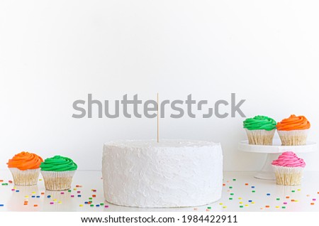 White Cake with cake topper stick and blank white background. With pink party decoration and colorful cupcakes, Cake topper mock up