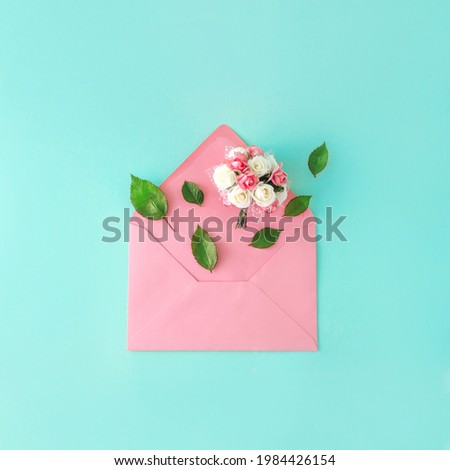 Flowers coming out of a pink envelope. Biedermeier. Blue background. Rose Petals.