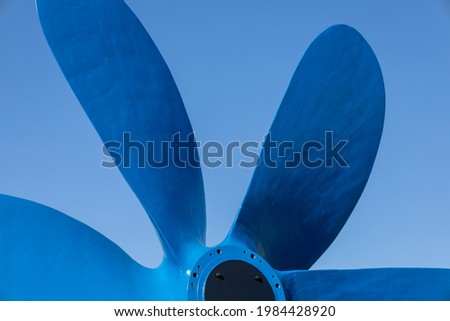 Large boat propeller painted blue against a clean blue sky background.  Shot in Sweden, Scandinavia