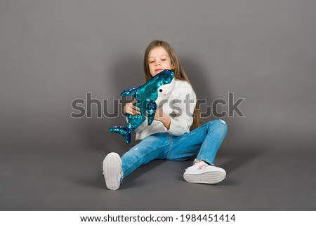 Young girl playing with shark toy in yellow studio