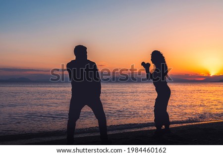 Karate fighters silhouettes in training on the beach on the sunset.