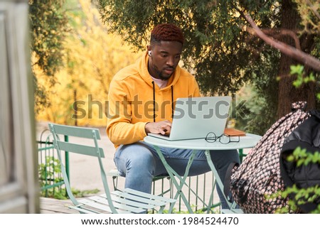 Man sitting with laptop at the table and looking attentively at the screen