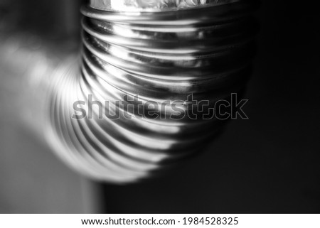 Black and white photo; close-up of stainless pipe with round corner on black-grey background.