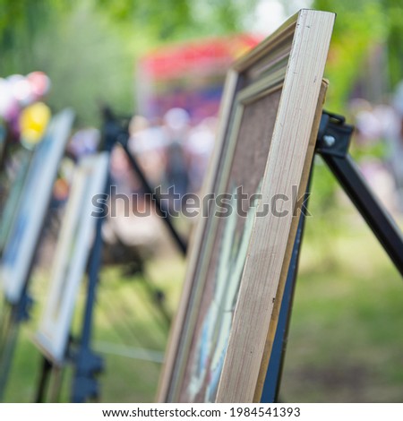 Exhibition. Paintings on easels in the park.