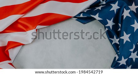 American flag lie on a cement background with space for text in the middle, top view close-up.