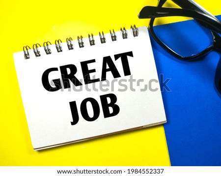 Business concept.Text GREAT JOB on notebook with glasses on yellow and blue background.