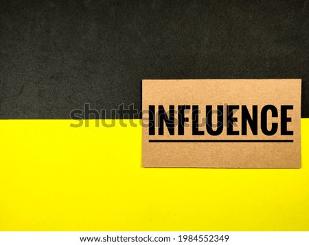 Business concept. Brown card with text INFLUENCE on black and yellow background