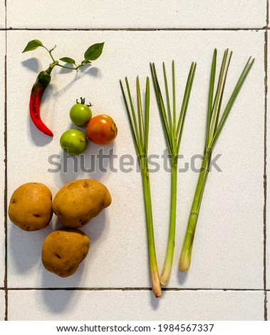 A picture of potatoes, a chilli pepper, tomatoes and three lemongrasses