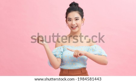 Young beautiful asian woman over pink isolated background Surprised pointing with finger to the side