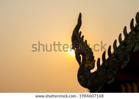A silhouette picture of Naga sculpture on tile roof of Thai traditional temple.