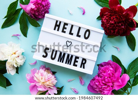 Light box with Hello Summer text and peonies flowers on a pastel blue  background