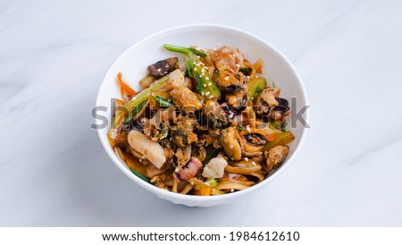 Udon noodles with seafood in bowl isolated on white.