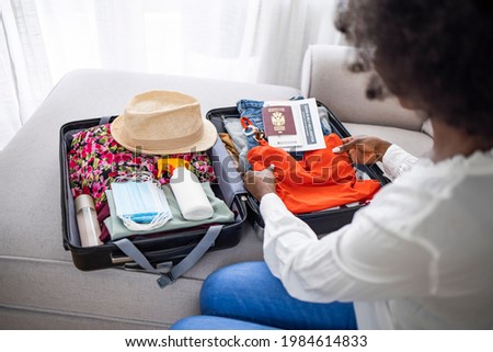 Woman packing suitcase for summer trip, including face masks and travel-sized antibacterial hand gels. Suitcase packing for travel, COVID-19. Woman packing suitcase for travel
