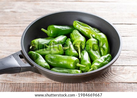 Fresh green pimientos or peppers de padron in frying pan. Fried in olive oil, and sprinkled with sea salt is a typical tapa meal in Spain. selected focus, narrow depth of field