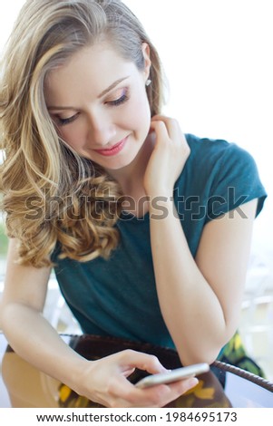 Happy teenage girl checks social networks holding smartphone at home. Smiling young woman using mobile phone app, playing game, shopping online, ordering delivery, relaxing. High quality photo.
