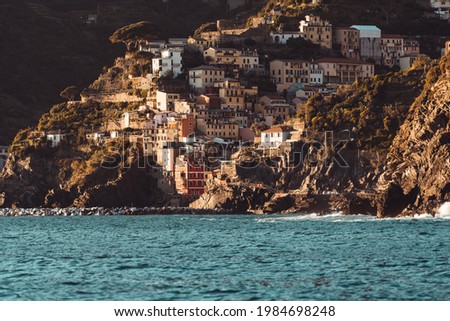 Riomaggiore, Cinque Terre, Italy. Sunset lights up the small Italian village on the mountain base.