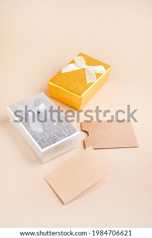 Business card mockup, eco kraft paper on a beige background and gift box for the holiday. Eco friendly stationery concept. Recyclable. High quality photo. Copy space. Vertical