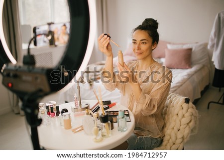 Young woman blogger recording video for social media demonstrating cosmetics. Makeup online tutorial.