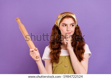Photo of mined dreamy young woman look empty space hold hand chin rolling pin meal idea isolated on purple color background