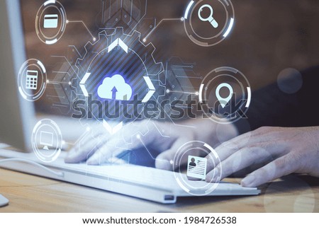Cloud computing concept with virtual cloud icon surrounded by card, magnifier, navigation mark and computer symbols on man hands on keyboard background