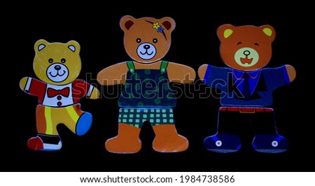 Children's figures of three colorful bears in clothes on a black background. Bear mom, Dad and bear cub. Holding hands