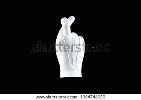 Human hand, hand in a white glove isolated on a black background, shows a gesture out of me. Human gesture concept cross fingers