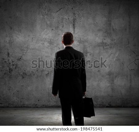 Rear view of businessman looking at blank cement wall