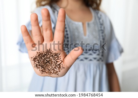 Little girl with henna tattoo on palm, closeup and space for text. Traditional mehndi ornament