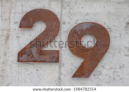 Rusty numbers of the number 29 on the background of a concrete wall. Original address of the house in Russia