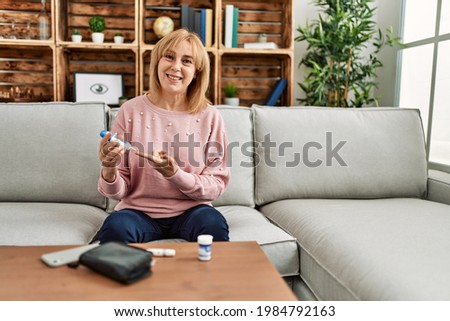 Middle age diabetic woman measuiring glucose using glucometer at home. Royalty-Free Stock Photo #1984792163