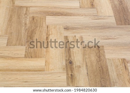 Laminate and parquet with herringbone background. Wooden floor with a chevron pattern in the living room of the designer interior