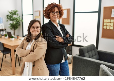 Group of two women working at the office. Mature woman and down syndrome girl working at inclusive teamwork. Royalty-Free Stock Photo #1984847762